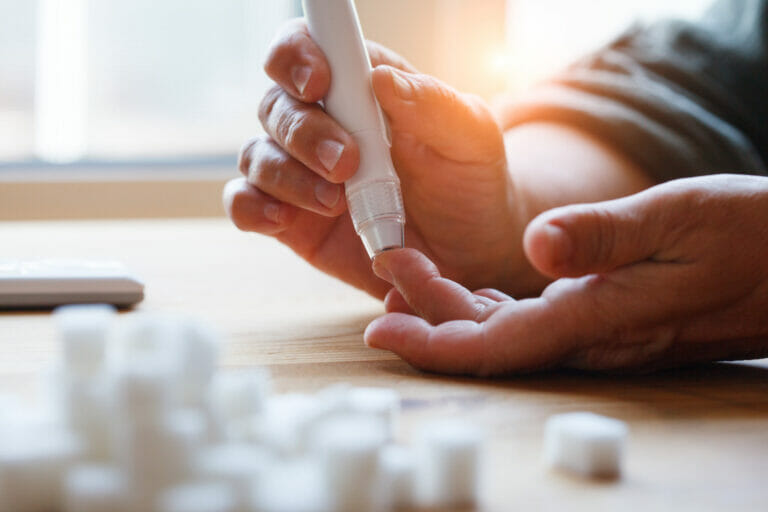 senior woman hands using lancet on finger at home to check blood